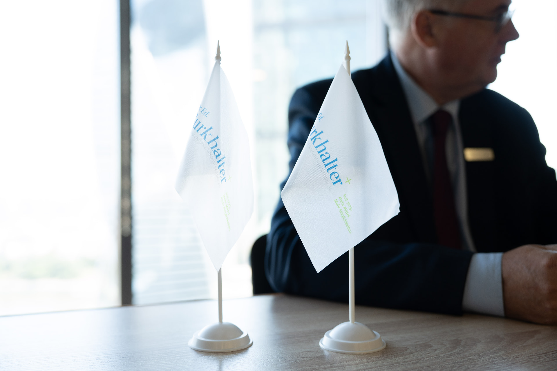Tischfahnen mit dem Signet der Dr. Ed. Burkhalter, Finanz- und Unternehmensberatung AG im Sitzungszimmer